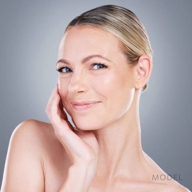 Woman with rejuvenated skin smiling touching face